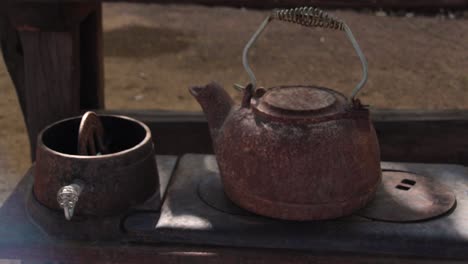 Pan-across-a-rusted-water-kettle,-and-antique-cooktop