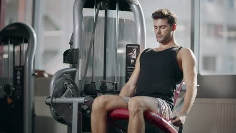 strong sportsman doing legs exercise on sport simulator in fitness club.