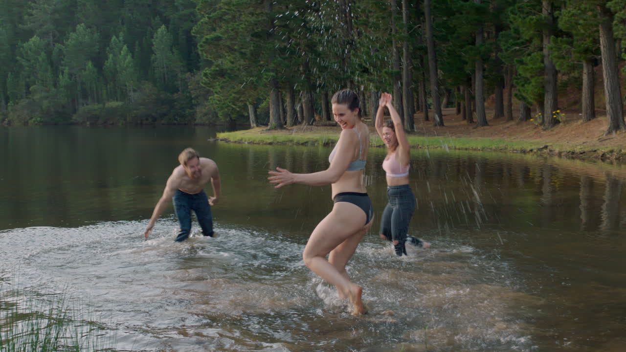 mejores amigos saltando en el lago al atardecer quitándose la ropa salpicando agua disfrutando de un juego juguetón jóvenes en vacaciones de verano aventura