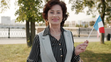smiling senior woman holding french flag