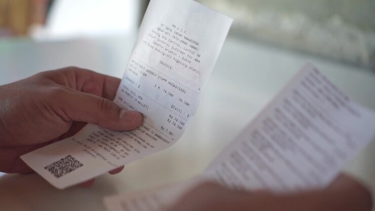 hand holding and reading payment receipt, checking bill details, financial transaction and expense concept.
