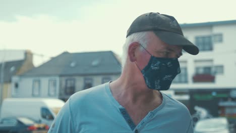 Mature-man-wearing-face-mask-reads-shopfront-sign-and-takes-out-phone