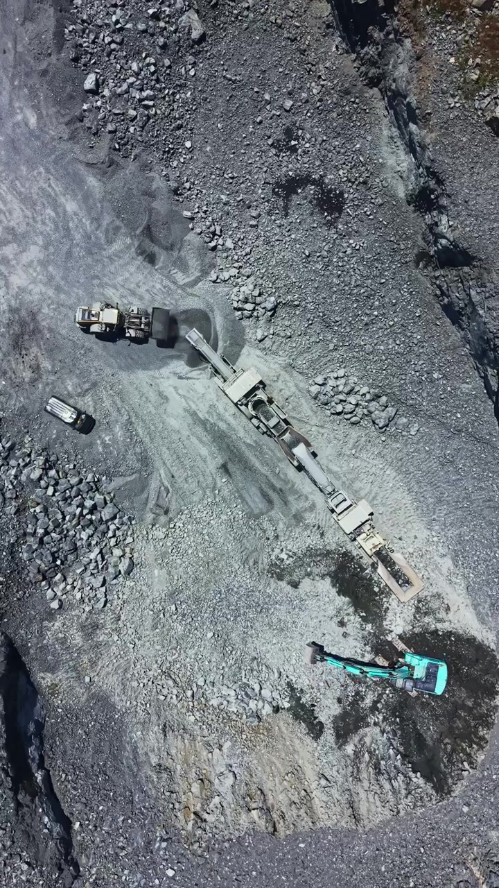 Excavation work in granite quarry shows heavy machinery moving materials at a mining site in the countryside during daylight hours