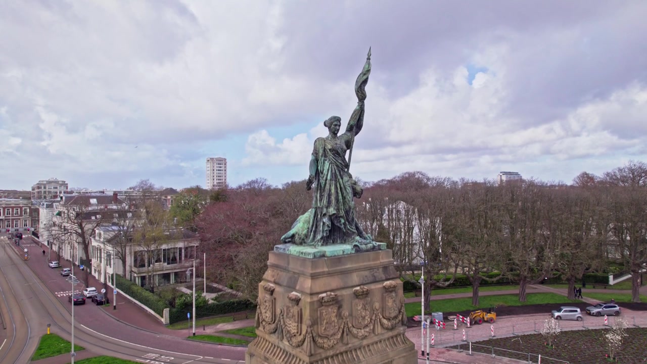 Plein 1813, ein Platz mit Kreuzung und Allee, mit vorbeifahrender Straßenbahn und Autos, der im Hintergrund das weitere Diplomatenviertel von Den Haag, Niederlande, zeigt.