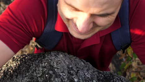 a man with a backpack climbs a rock trying to get to the top. the concept of overcoming adversity alone.