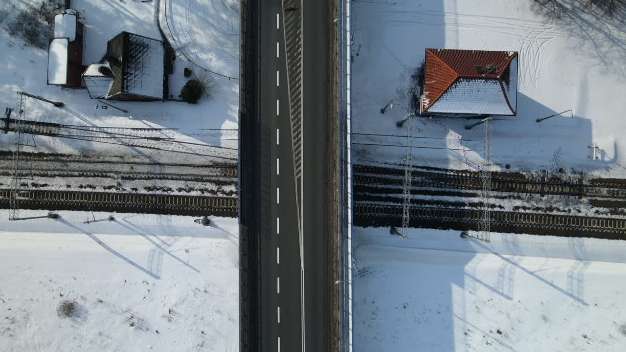 겨울 풍경의 드론 하향식 철로 육교, 흰색 방향 화살표가 있는 검은색 아스팔트 도로