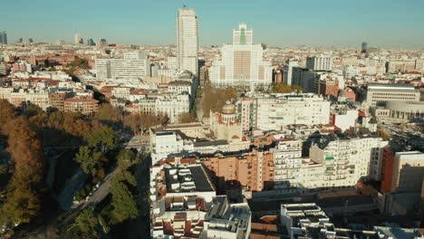 Fly-above-buildings-in-city-centre.-Historic-skyscrapers-at-Spain-square-in-bright-afternoon-sunlight.