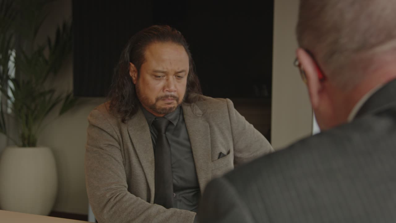 A young businessman eagerly explains his ideas to his boss in a corporate office