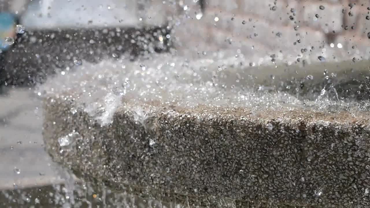 Nærbillede af vand der sprøjter på et springvand af sten