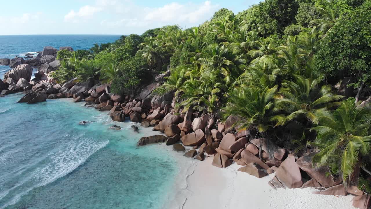 Flygvy över de vita stränderna och det turkosa vattnet vid Anse Coco, Petit Anse och Grand Anse på La Digue, en ö i Seychellerna