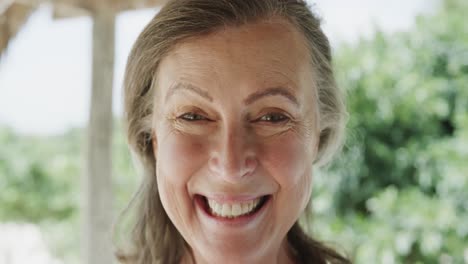 Portrait-of-happy-senior-caucasian-woman-smiling-on-beach,-in-slow-motion