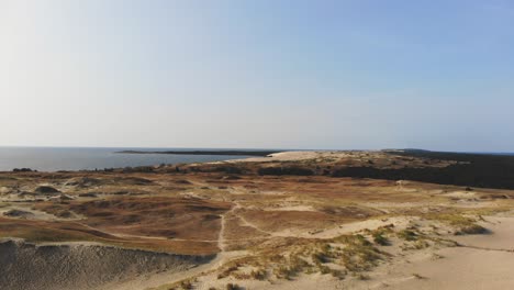 AERIAL:-flying-over-sunny-sand-dunes-towards-the-sea-in-the-evening