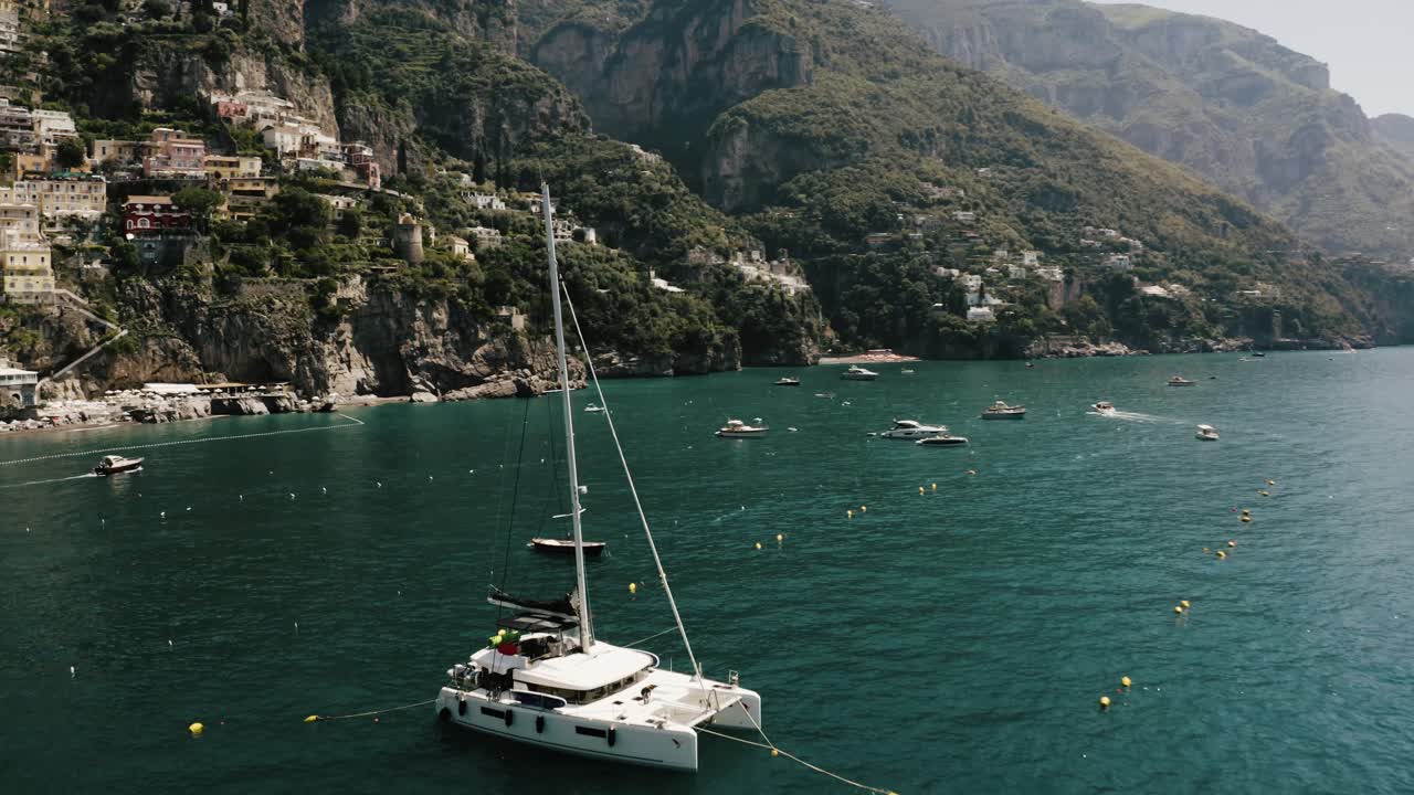 drone filmado volando por barcos sentados frente a la costa de positano, italia