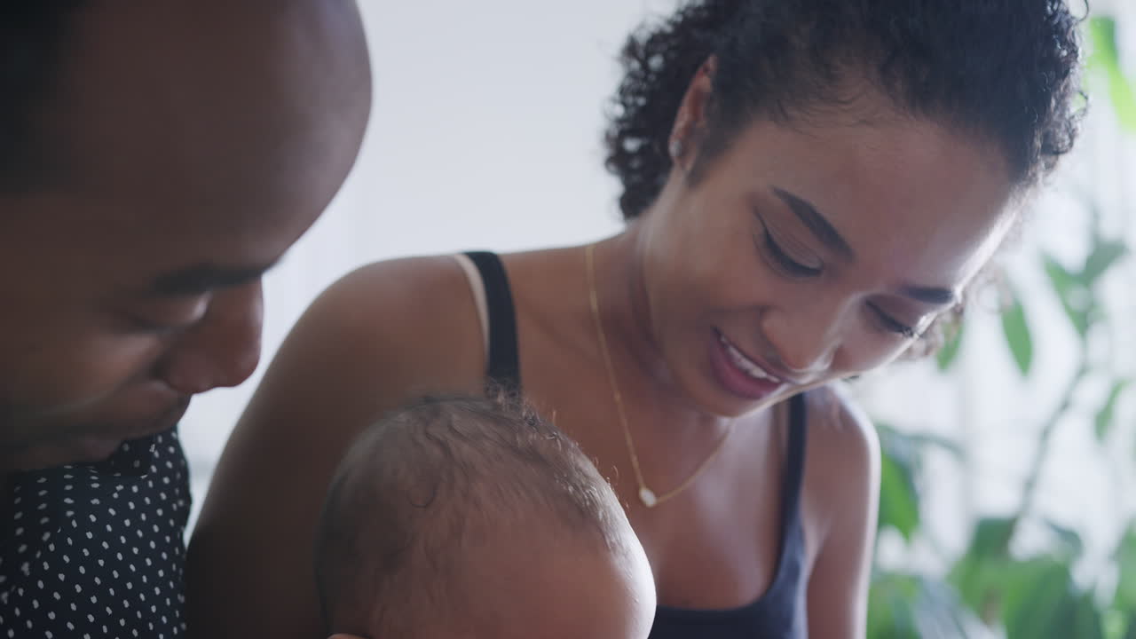 Close Up Of Loving Parents Playing With Baby Daughter Sitting At Home Together