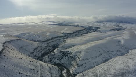 wide pulling back drone shot of expansive snowy plains and canyons