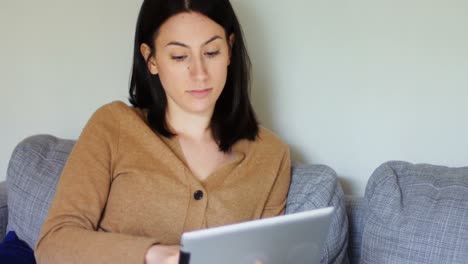 mujer joven usando tableta digital en el sofá 4k