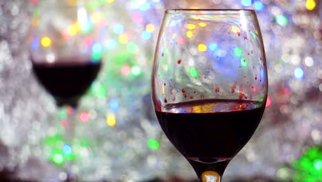 copa de vino tinto en primer plano sobre un colorido bokeh y una manta plateada de cerca en un ambiente íntimo y romántico
