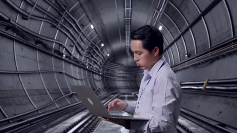 side view of an asian male professional worker use laptop in underground subway tunnel,  he is nodding his head with dissapionted