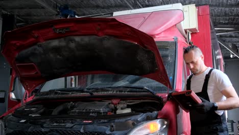 mechanic inspecting a truck engine with a diagnostic tool in a garage