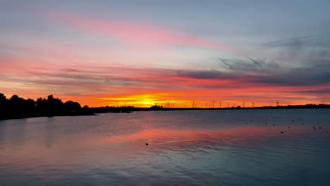 impresionante puesta de sol sobre el mar báltico en puck, polonia con molinos de viento en segundo plano