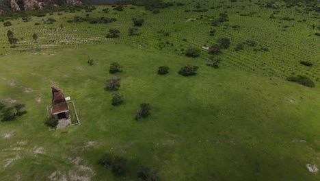 Rustic-hand-built-fireplace-oven-pit-in-empty-grassy-rural-green-field-mountain-countryside-aerial-view