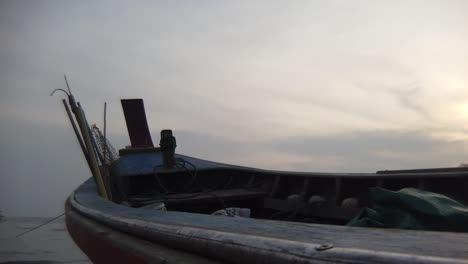 close-up view of the front of a long tail boat floating peacefully on the water in the early morning hours, thailand.