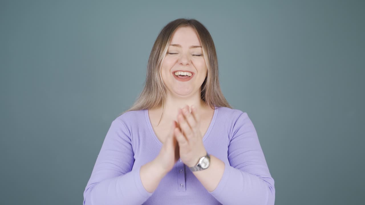 젊은 여성이 카메라에 흥분해서 박수를 치고 있습니다.