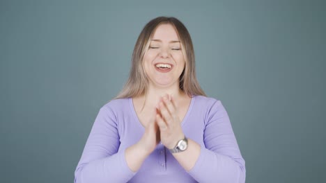 una mujer joven aplaudiendo emocionada a la cámara.
