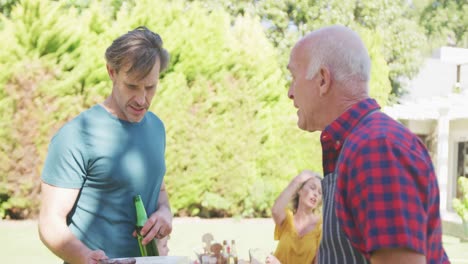 Happy-caucasian-family-having-barbecue-and-eating-in-garden