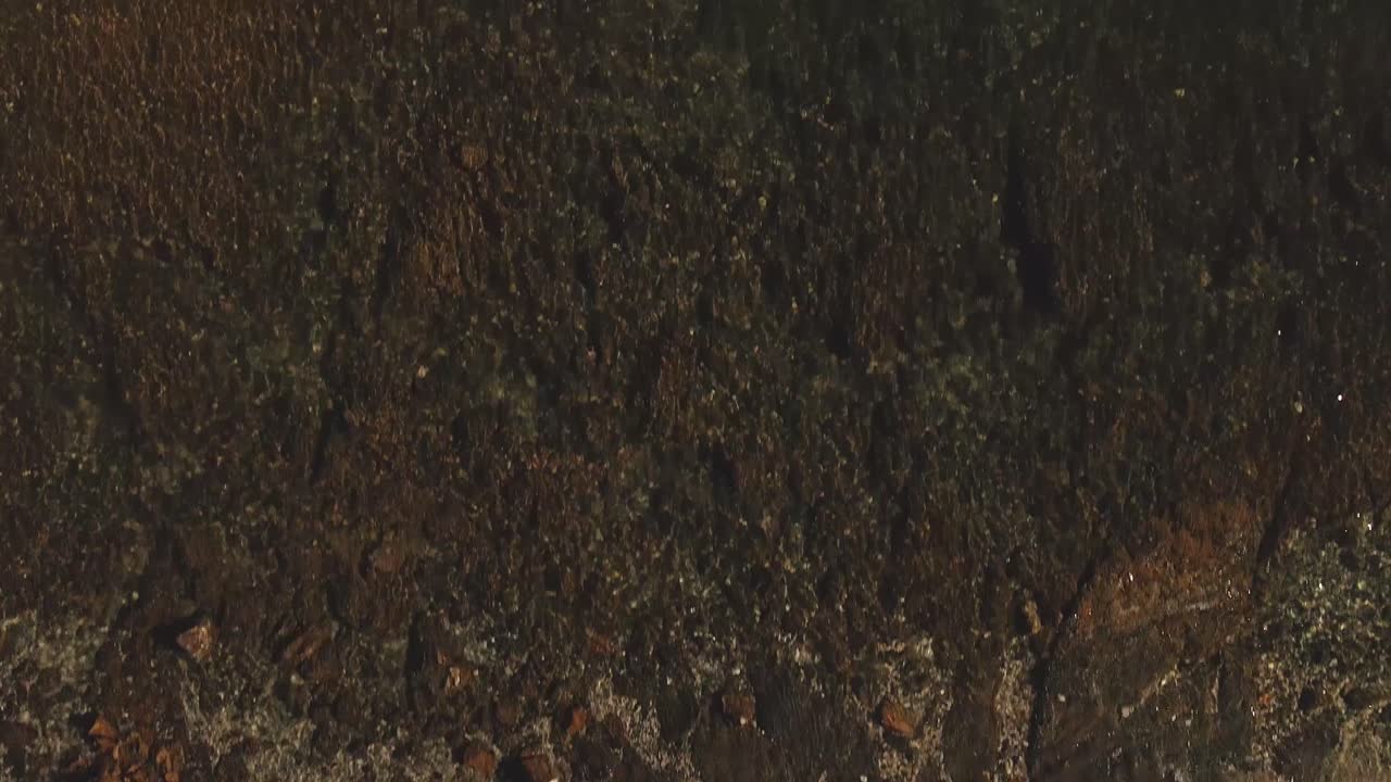 vista aérea de pájaro sobre las olas de la costa arenosa que se inclinan hacia el barco que viaja a través del paisaje marino del océano