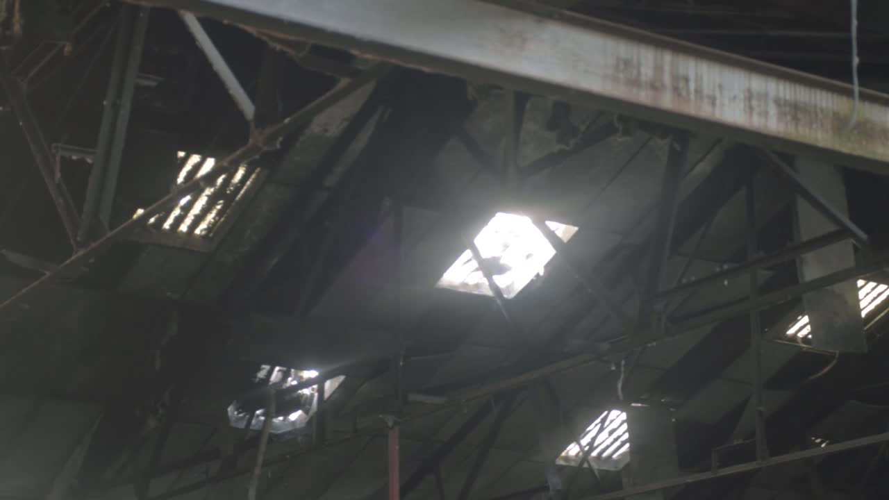 Corrugated broken roof windows of derelict building panning shot