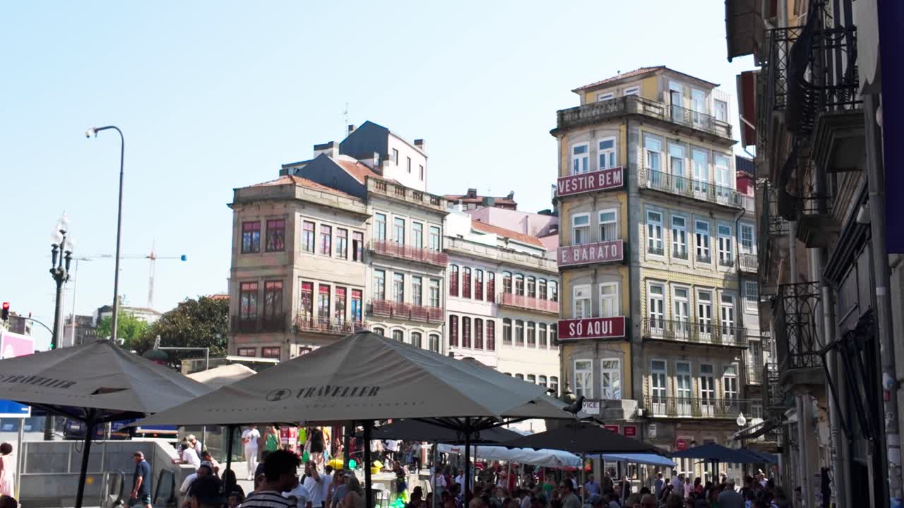 People sitting at outdoor café on cobblestone street in Praça de Almeida Garrett, Porto