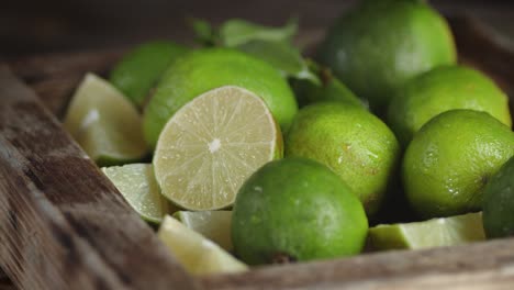 fresh limes in a wooden box slowly rotate.