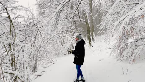 man shaking snow from tree branches and the flaky snow is falling down - wide shot, slow motion