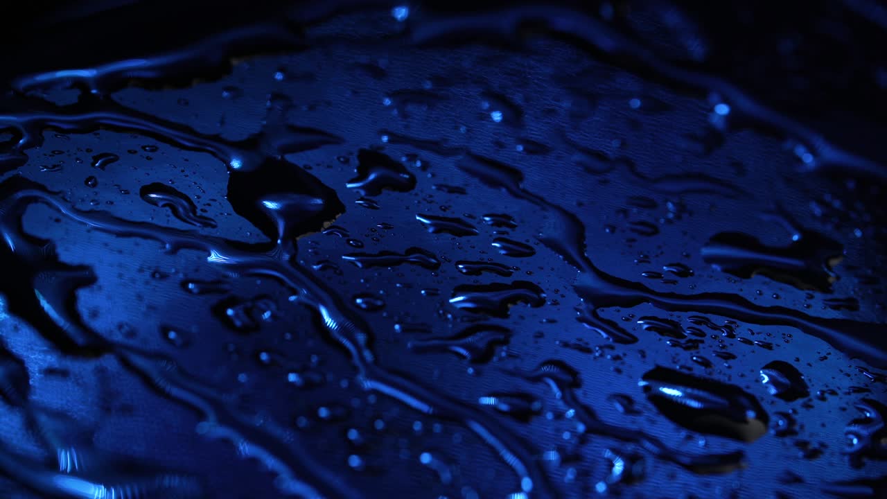video de gotas de líquido sobre un fondo azul oscuro