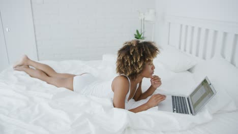 mooie vrouw loungen op bed met laptop