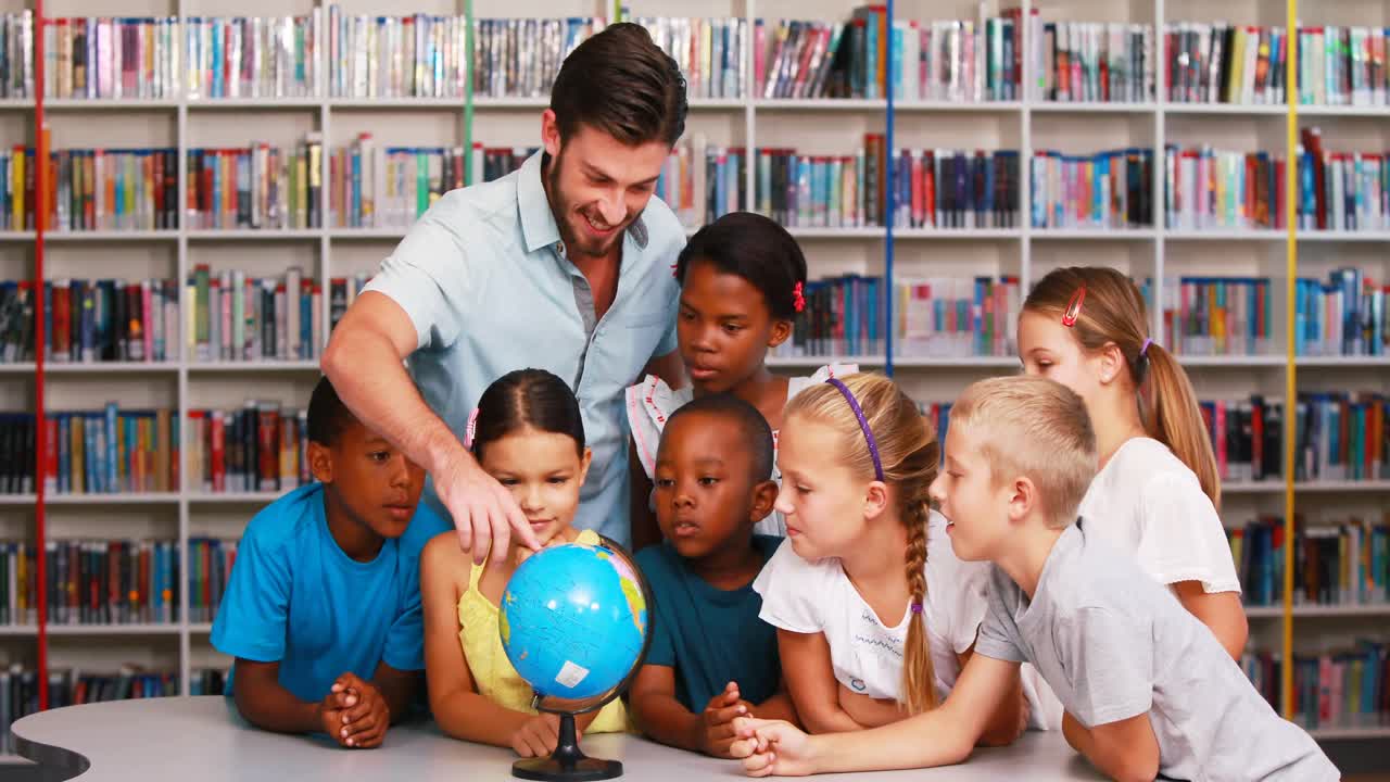 niños de la escuela y el maestro mirando el globo en la biblioteca