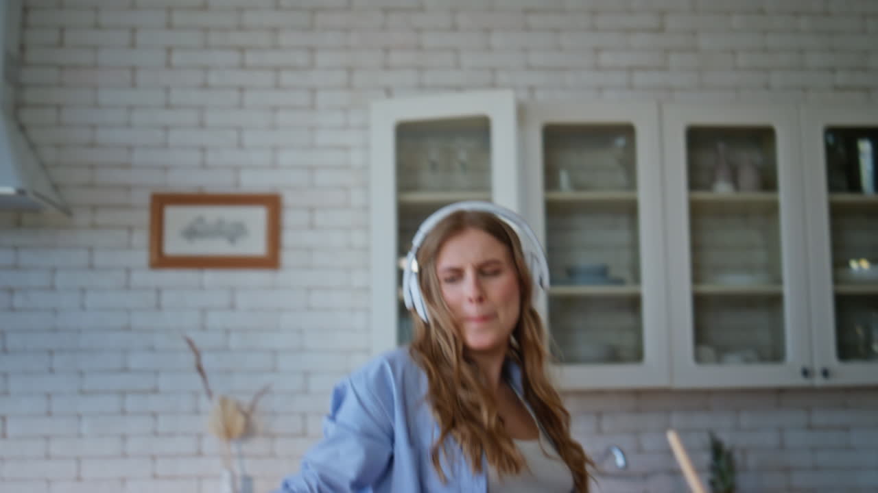 Headphones woman dancing kitchen closeup. Happy girl rejoicing in house alone