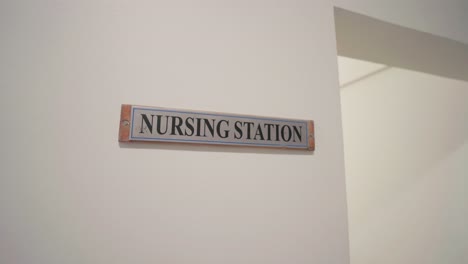 a clear nursing station sign mounted on a white wall in a healthcare setting.