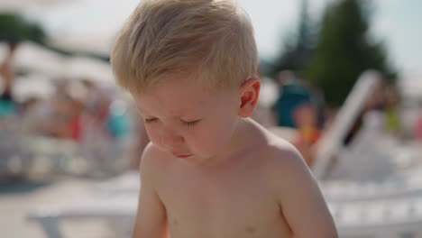 toddler boy sneezes resting on beach at marine resort