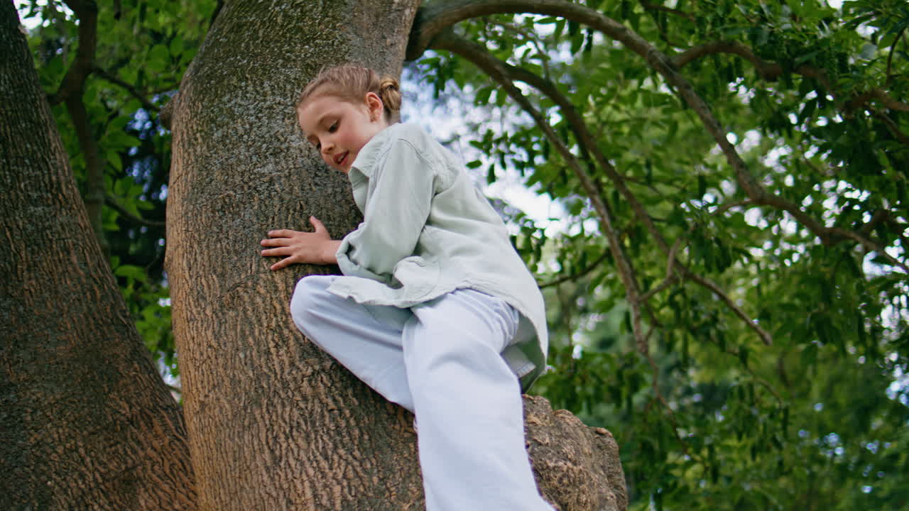 Small girl climbing tree walking forest closeup. Curious kid feeling active