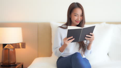 Una-Mujer-Bonita-Sentada-En-Una-Cama-Disfruta-Tranquilamente-Leyendo-Un-Libro