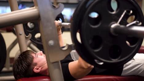 closeup of young bodybuilder lifting weights and bench pressing