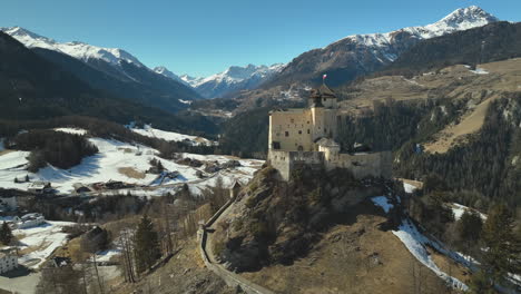 drone dolley shot of ancient schloss tarasp between the high mountains of the swiss alps