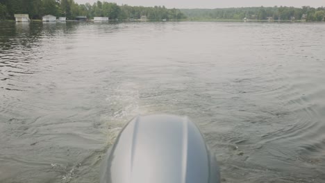 outboard motor of sailing boat with traces on a tranquil lake