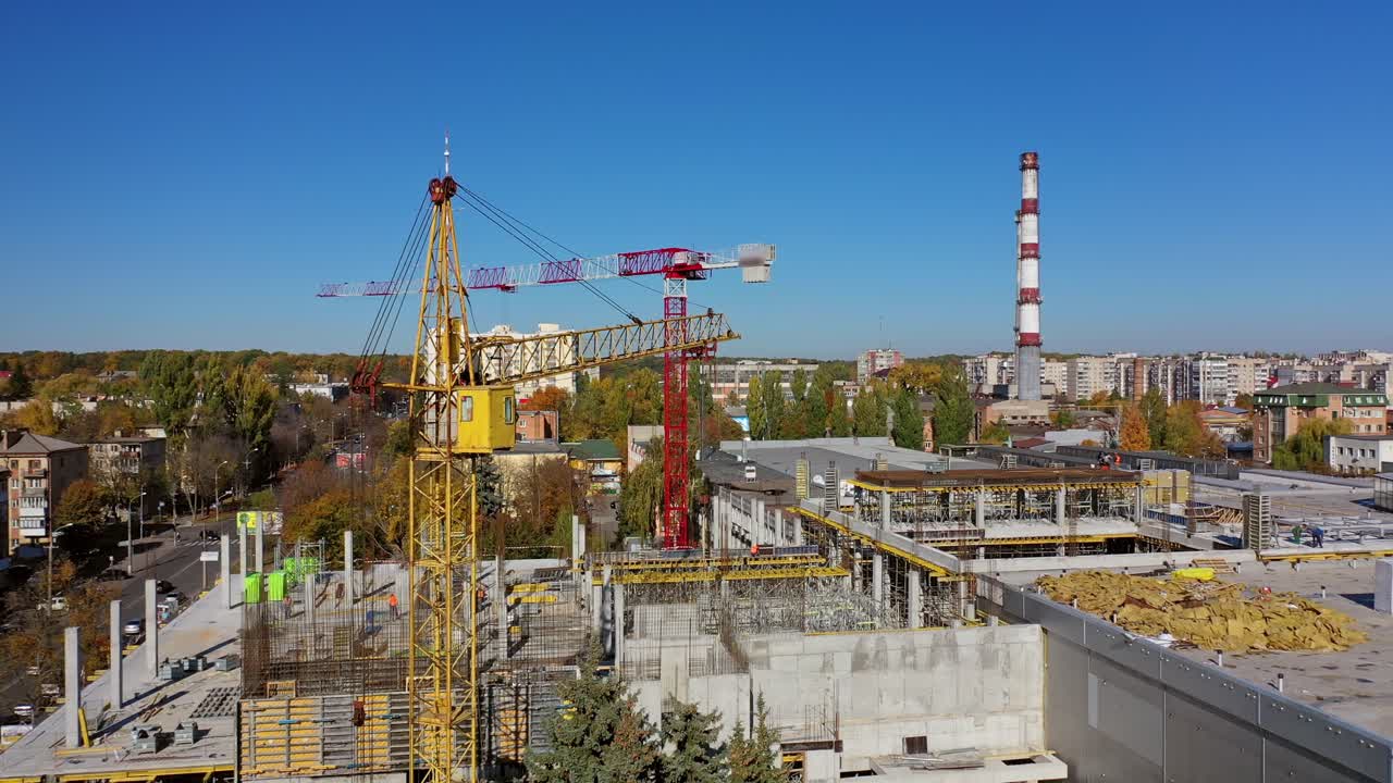 Construction of a new shopping center. Urban background and two cranes on construction site. Video shooting with drone.