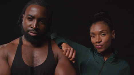 close up studio portrait of determined male and female athletes training in fitness clothing shot against black background