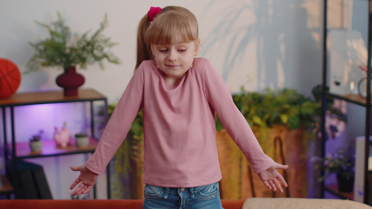 Confused little child girl kid at home having doubts, no idea, being clueless and uncertain, shrugs