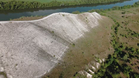 aerial view of a hill with white rock formations and a forest