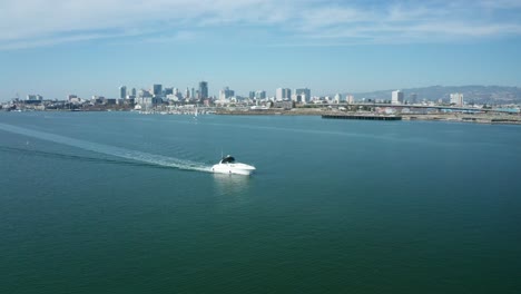 Ein-Einsames-Segelboot-Durchquert-An-Einem-Sonnigen-Tag-Die-Bucht-In-Der-Großstadt